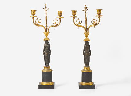 A pair of French Empire gilt and patinated bronze candelabras, first quarter 19th century Of: A pair of French Empire gilt and patinated bronze candelabras, first quarter 19th century Of Neoclassical form, with caryatids supporting scrolled candle cups, on black marble bases. H: 20 ¼ in