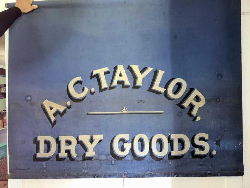 Advertising Sign, A.C. Taylor Dry Goods on patent: Advertising Sign, A.C. Taylor Dry Goods on patent shade roller, blue shade, white letters, 69"Wx8' long approx.
