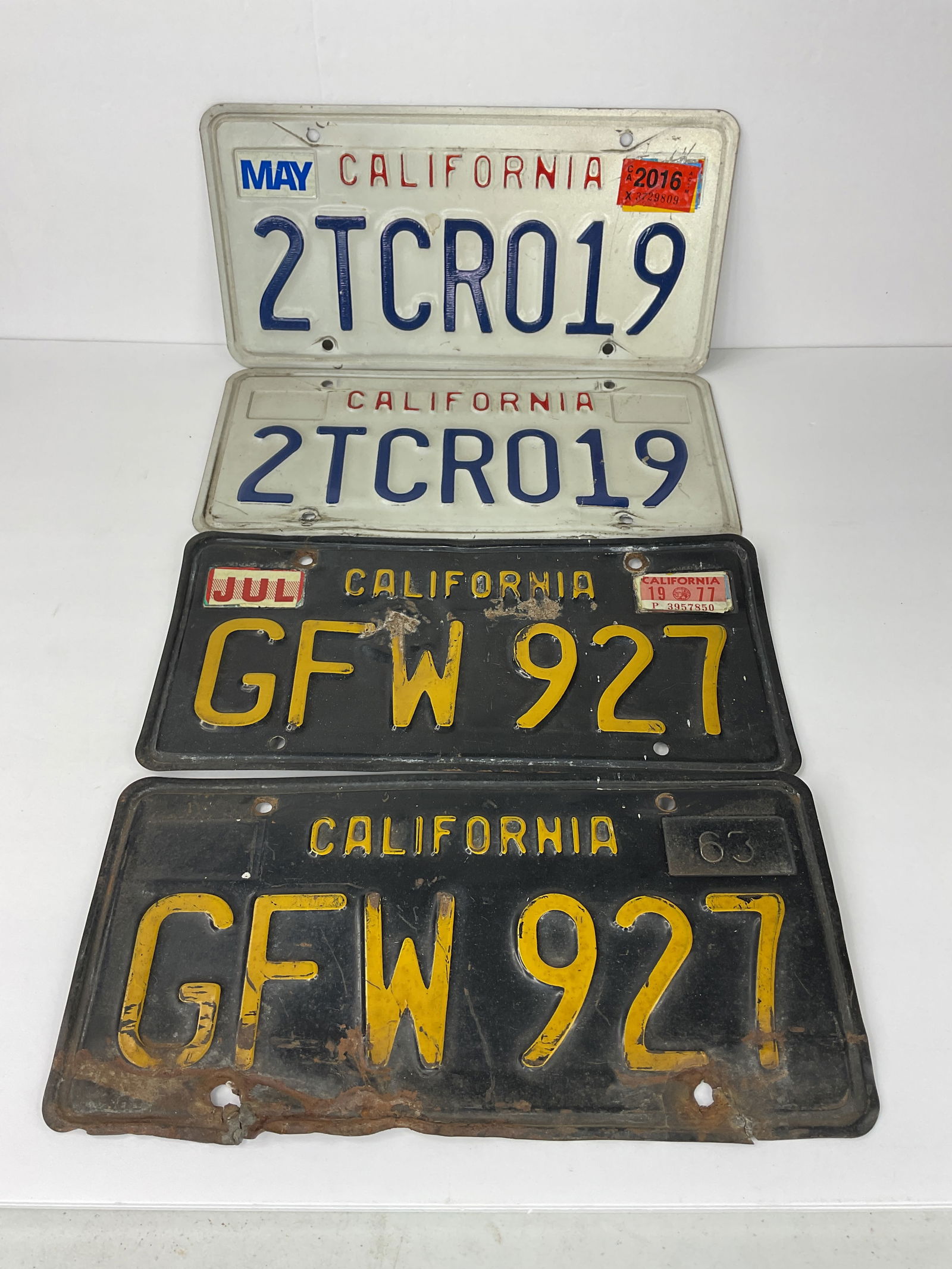 (2) MATCHING PAIRS of California LICENSE PLATES 1963 GFW 927 Red White Blue 2TCR019: (2) MATCHING PAIRS of California LICENSE PLATES BLACK & GOLD 1963 GFW 927 Red White Blue 2TCR019. Both show age wear and 1963's show rust and lots of bends