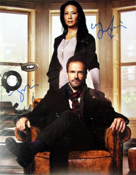Lucy Lui / Johnny Lee Miller ELEMENTARY 11x14 IP Signed: 11x14 Lucy Lui and Johnny Lee Miller in person signed autographed photo from the TV series ELEMENTARY. Lucy Lui as the character Dr. John Watson / Johnny Lee Miller as the character Sherlock Holmes