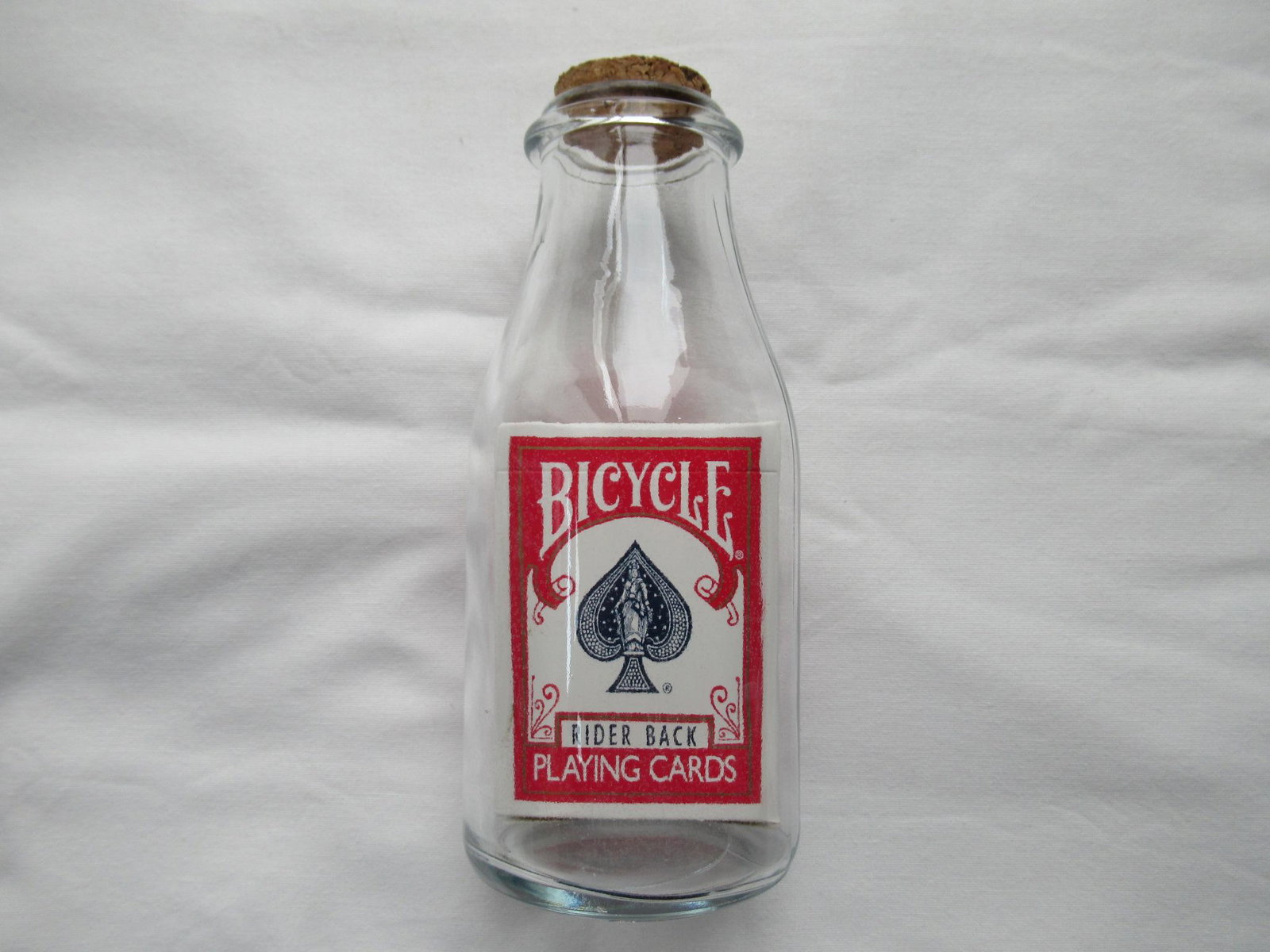 Playing Cards Impossible Deck in Bottle: A box of Playing Cards inside a glass bottle that is non tampered with or altered in any way and a glass mouth smaller than the deck inside. The glass has not been cut, melted, formed around the cards