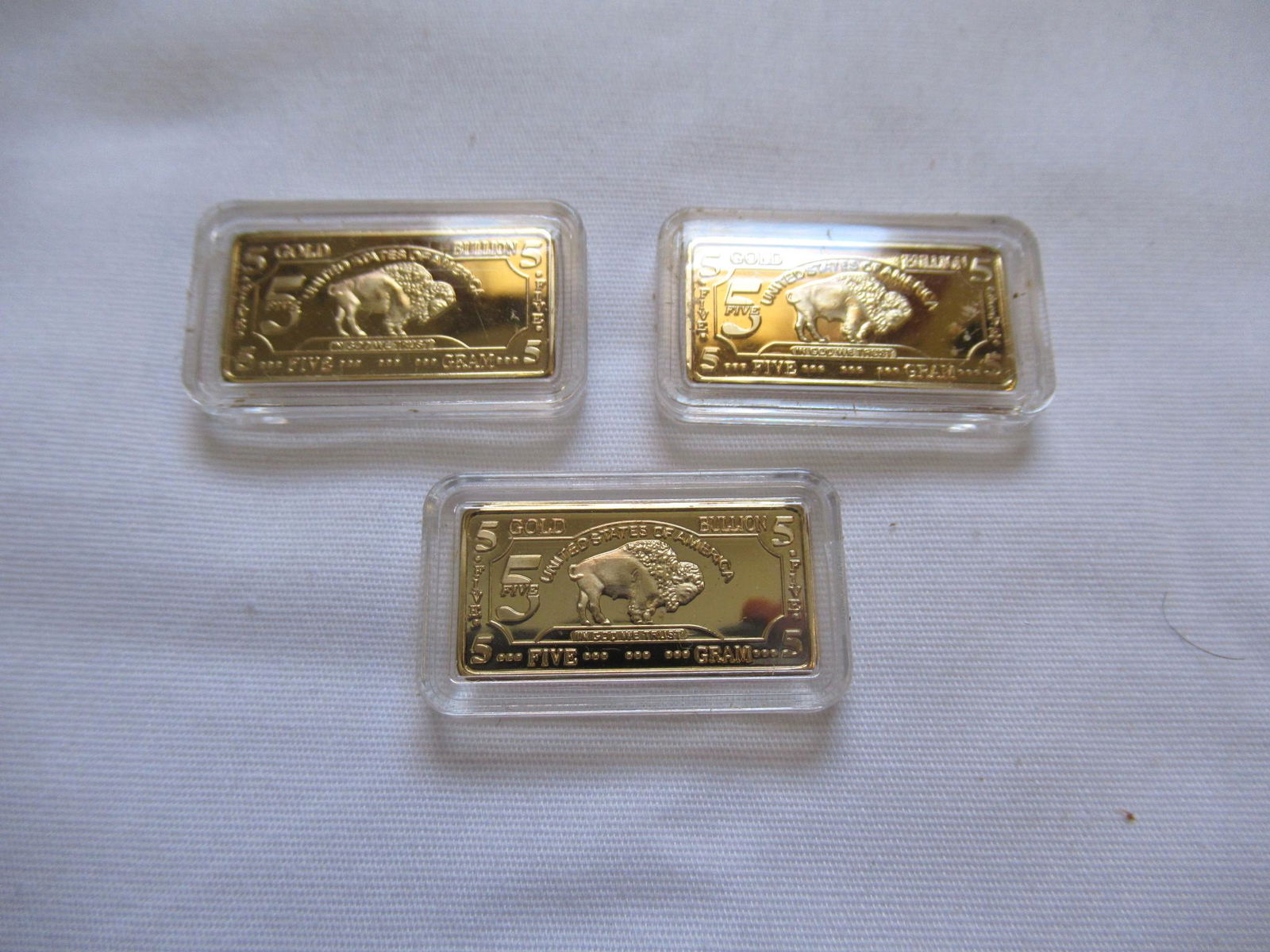 (3) 5 Gram 100 Mills Gold BUffalo Bullion Bars .999 Fine 24K Bullion: 5 gram American Buffalo 100 mills gold clad bar. 5 grams total- come in hard plastic capsules. These bars are .999 fine GOLD CLAD