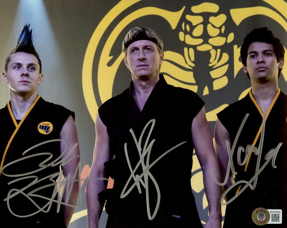 Zabka / Mariduena / Bertrand COBRA KAI In Person Signed Photo: Photo size is 8x10. PRIVATE SIGNING. From a EBAUTOGRAPHS signing. Beckett authentication. William Zabka / Xolo Mariduena / Jacob Bertrand in person signed autographed photo from the TV series COBRA KA
