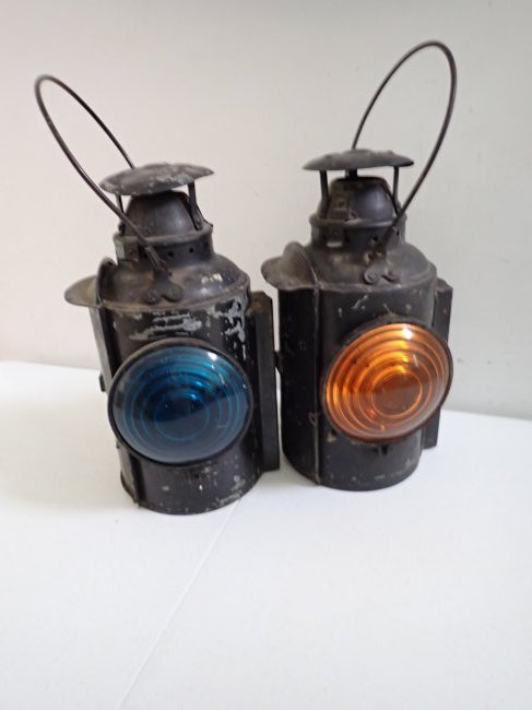 CNR Montreal Piper Pair Caboose Lanterns: One with Yellow Lens and other with Greenish Blue Lens 14" High with Bail handle lifted 18". Have kerosene burners. Have some wear and show use with dents on top.