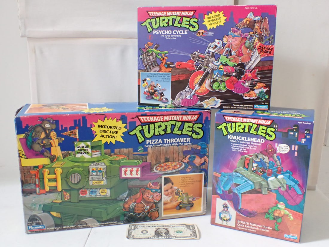 (3) 1980's Teenage Mutant Ninja Turtles Toys in Boxes: Pizza Thrower, Psycho Cycle and Knuckle Head. Psycho Cycle and Knuckle Head are Tape Sealed in Boxes. Psycho Box has edge creasing and minor wear. Knuckle Head has light wear and Pizza Thrower box is 