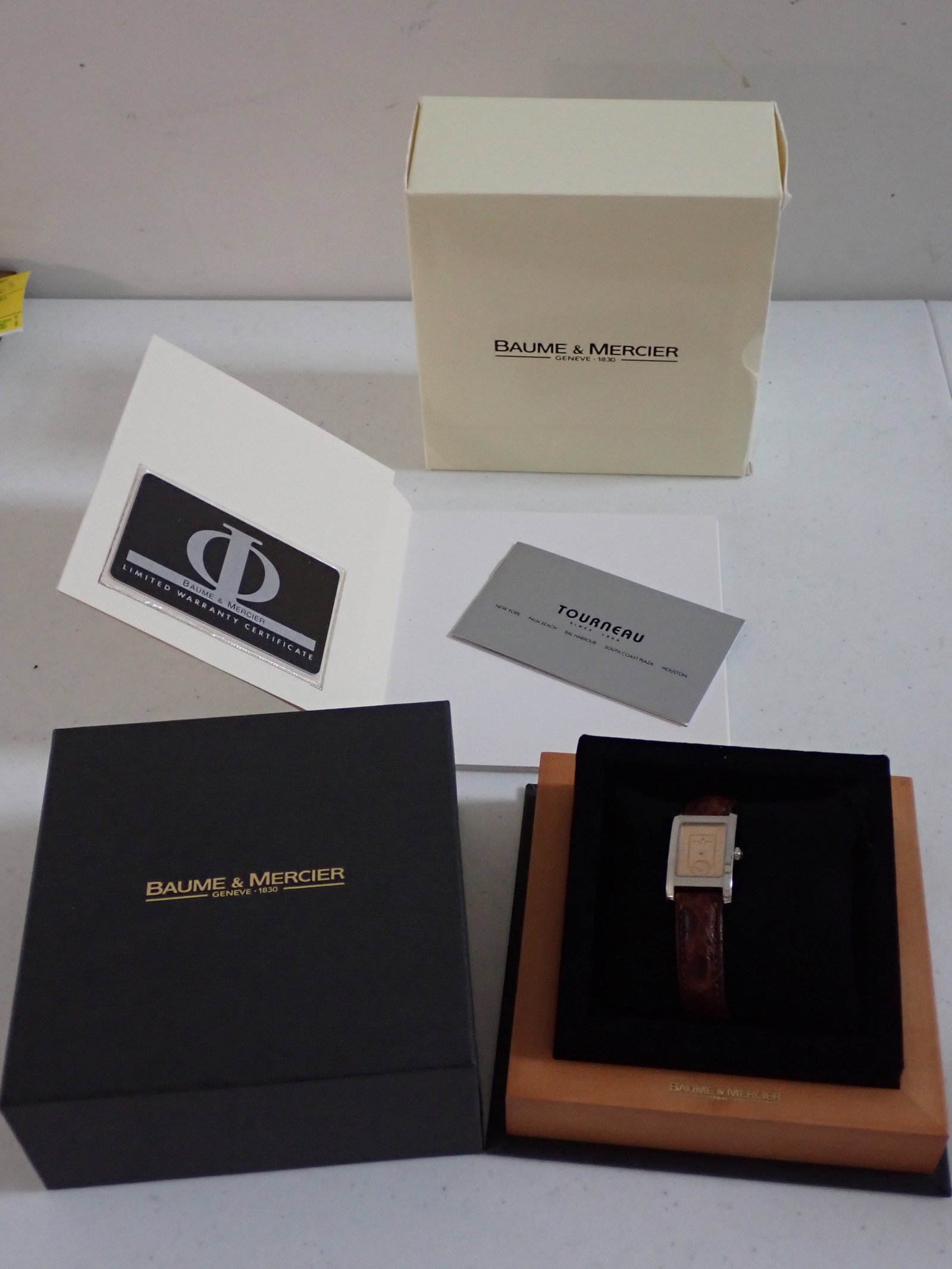 Baume & Mercier Men's Watch with Original Packaging: Baume & Mercier Men's Wristwatch gold colored dial stainless back. Has original packaging with pamphlet, warranty card, tag and instructions.The case is 5 1/4" x 5 1/4". on top and 5 5/8 x 5 5/8" on b