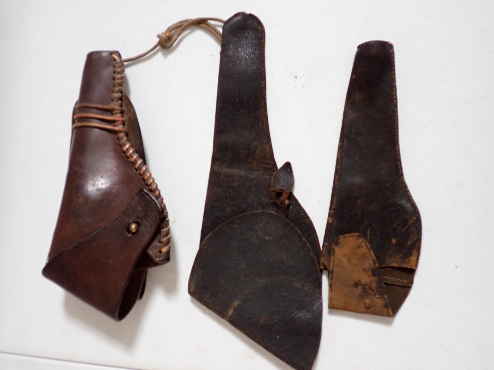 Leather Holster with Raw Hide and 2 Others Holsters: 11" Holster with rawhide trim has a little wear. Other holster 9". Has wear most noticable on flap. 14" Holster has some wear with tearing where flap attaches to clasp.