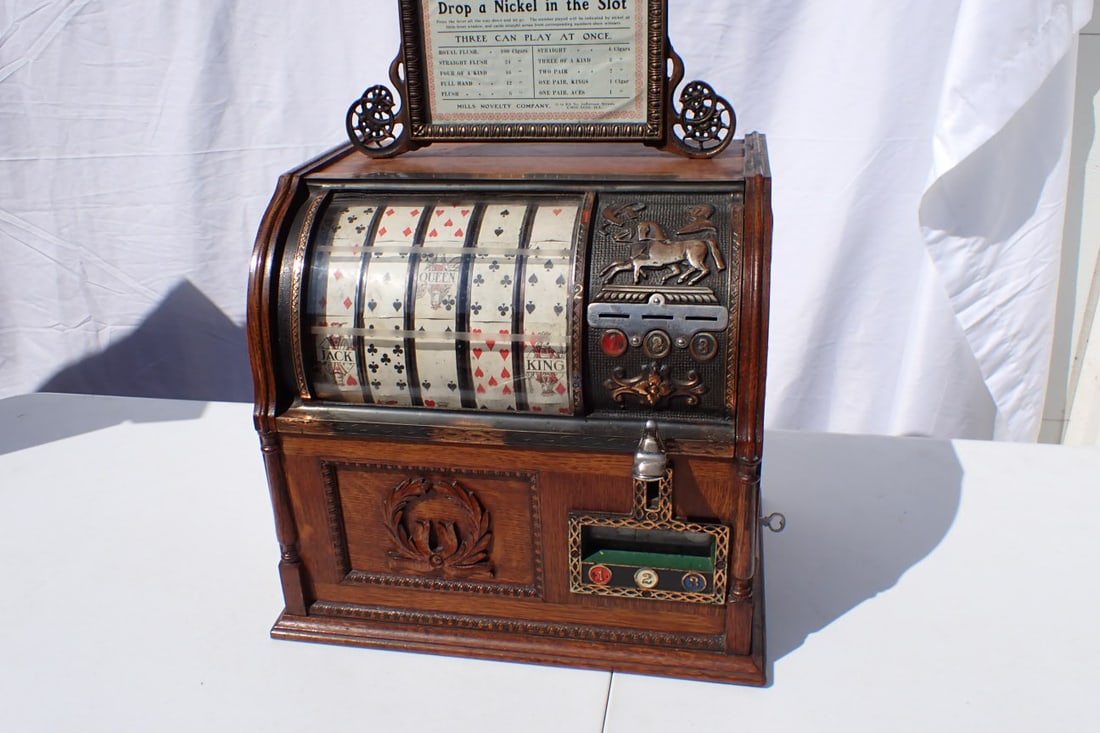 Mills Five Cent Jockey Poker Hand Trade Stimulator/Slot Machine - Works: Mills Five Cent Jockey Poker Hand Trade Stimulator/Slot Machine. Chicago, ca 1900. Five Real Trade Stimulator in oak cabinet with fancy cast metal marquee, round glass front covering five reels playin