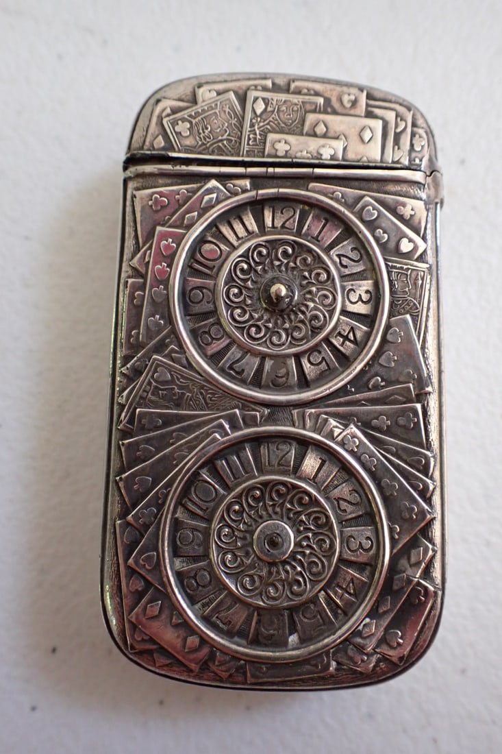 Roulette and Playing Cards Gambling Matchsafe: One side has two roulette wheels and playing cards. Opposite side has ornate design w/ spades symbol.