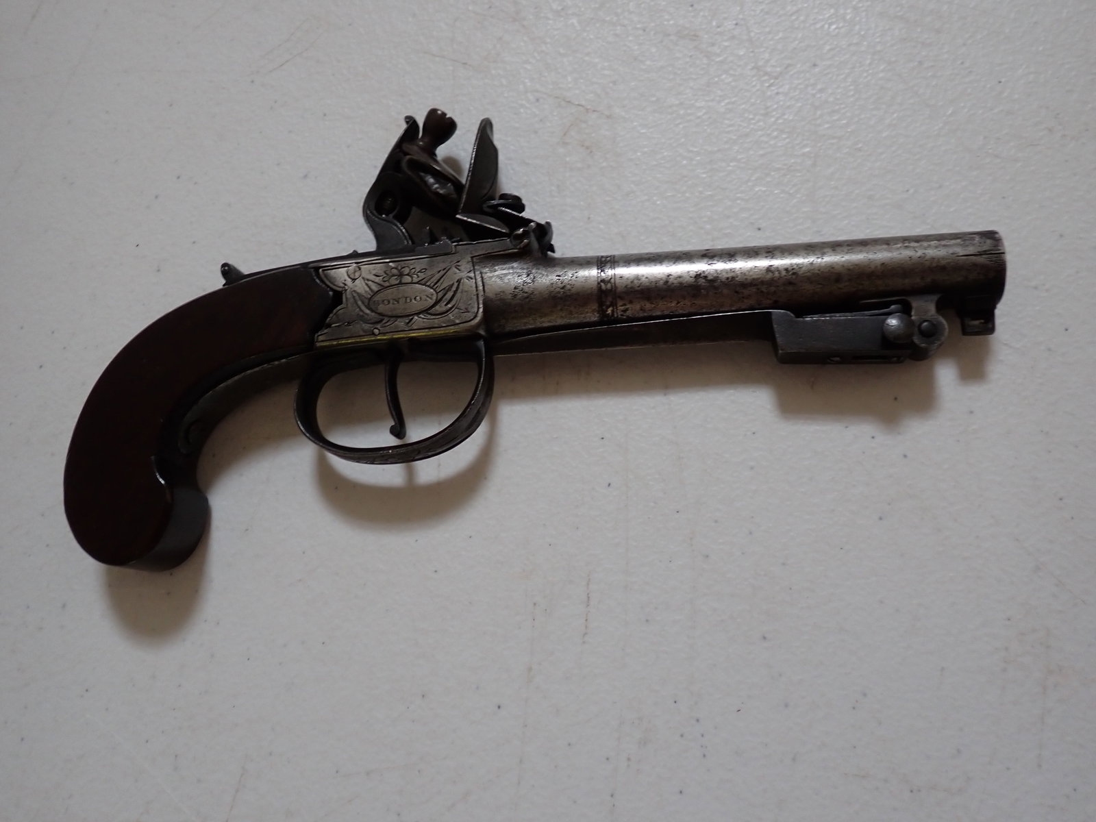 Dutton English Flintlock Pistol with Bayonet: Marked "Dutton" on one side and "London" on the other. Trigger mechanism works. 8". 4 1/4" Barrel. Has 3" Bayonet that opens when Trigger Guard is Slid Back. Photo of estate description is included.