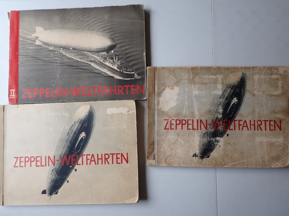 3 1930's Zeppelin-Weltfahrten Cigarette Card Books: 3 German Books about Zeppelins with inserted Cigarette Cards. Duplicate copies of 1932 Edition 1, copy of the second edition from 1933. 1 copy of the 1932 book is in good condition with cover wear. Ot