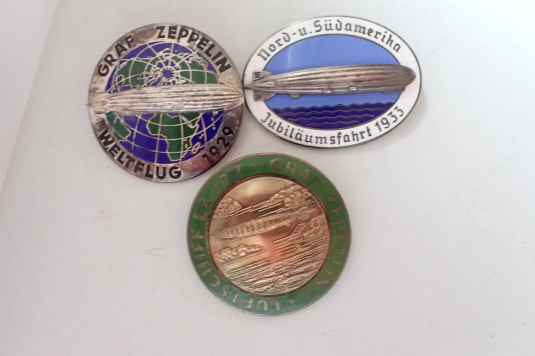 1933 North & South American Graf Zeppelin Pin & other Pins: 1933 Nord-u-Sudamerika. Luftschiff LZ 127 Graf Zeppelin, 1929 Graf Zeppelin Weltflug Pin. 1929 Pin has Most Wear. 1933 has wear mostly on the back. The other pin has lighter wear.