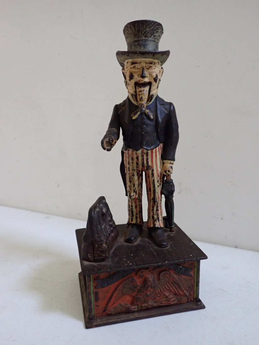 Uncle Sam Cast Iron Mechanical Bank Shepard Hardware 1886.: Shepard Hardware Co. Patented 1886. Cast iron and hand painted Uncle Sam. Lever causes coin to drop in satchel and beard to wiggle. Has some wear and paint loss but overall good. Door to retrieve coin