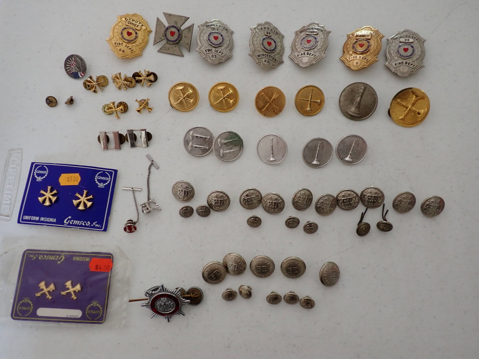 Worcester Fire Department Chief, Captain and other badges, pins and buttons: 6 Badges, Hat emblem, buttons marked FD, pins with fire trumpets and English Hereford & Worcester Fire Brigade pin and buttons.