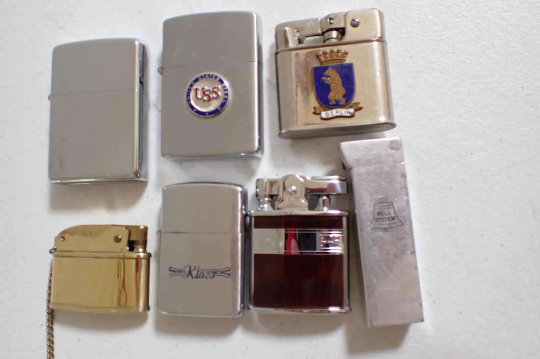 Bell Telephone, US Steel, and other Cigarette Lighters - 7 Total: Bell telephone lighted. Inscribed: R.A. Salomon New Eng. Tel & Tel Co. (Telephone and Telegraph). US Steel Zippo Lighter. Berlin Coat of Arms Lighter. Klozo Wellington Lighter. Gold colored Bomart. Ro