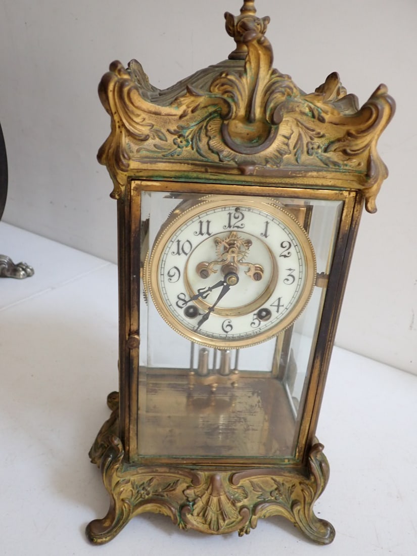New Haven Porcelain face iron and beveled glass case Clock: Ornate design clock. Face marked Made by the New Haven Clock Co .New Haven, Conn. U.S.A. 15 1/2" high with pendulum and key. Pendulum moves but clock has been over wound.