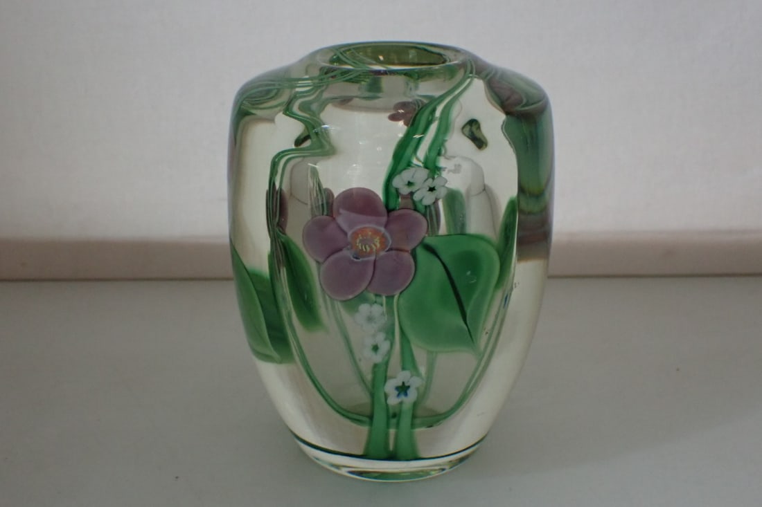 Orient & Flume Paperweight Vase: with encased purple and white flowers and green leaves. Engraved O&F 1987. 3 1/2" diameter x 4 3/8" high. No significant damage. Light wear from use with one scratch on the side and a few pinhead size