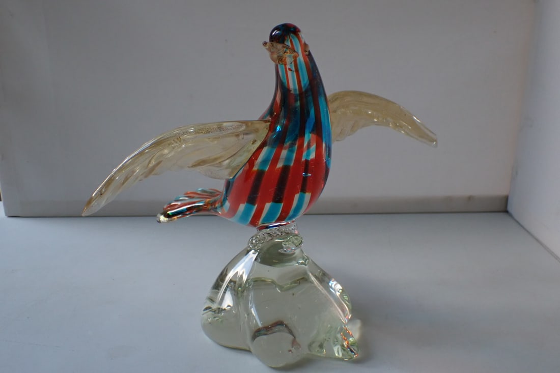 Murano Art Glass Bird Figurine: red and blue colored glass body with gold-flecked wings on a clear glass base. Unmarked. 9 5/8" wide x 7 1/2" deep x 8" high. No cracks or chips. Light wear from use.
