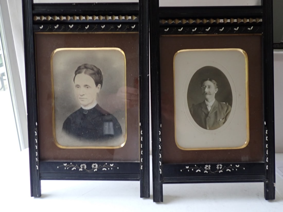 Photo of Man and Woman in Victorian Frames: Victorian hand tinted photo of Woman and Photo of Man. In Black Easel Back Frames with Floral and Scroll Designs. 16 1/2" x 9" each.