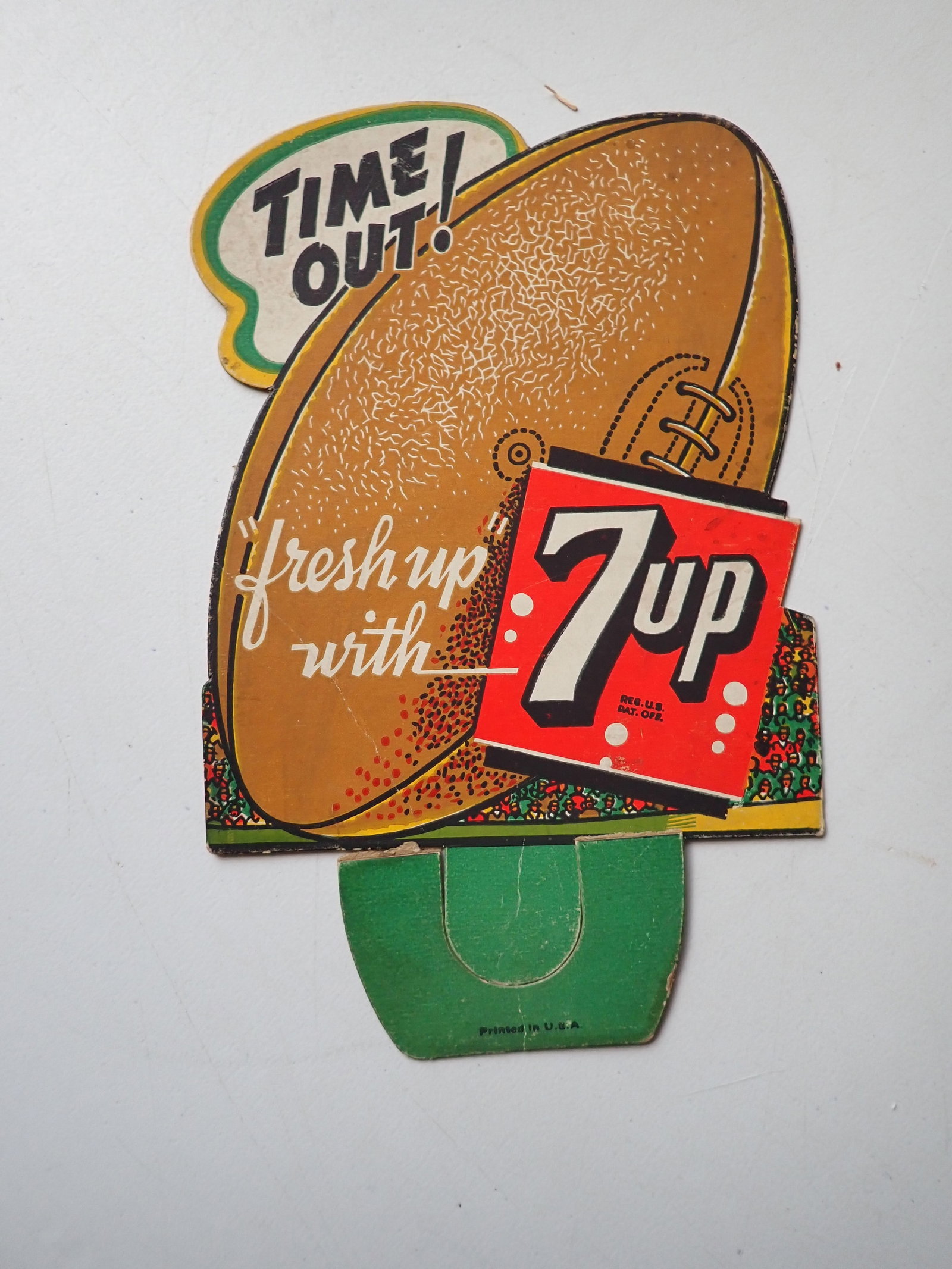 7up "Time out! Fresh up" football die-cut advertising cardboard sign: Football graphic with "printed in U.S.A." on base. 8" x 5". Base is torn. Has crease.