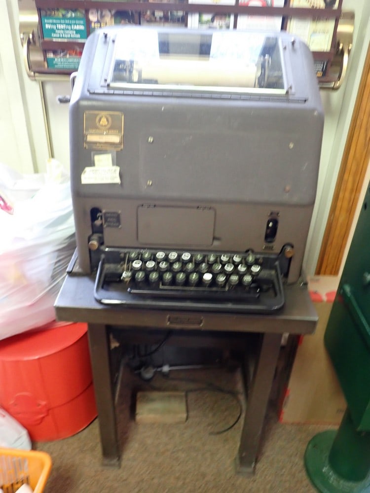 Bell Telephone Service Teletype with table: Metal machine with stand and pamphlet. 42" x 16 1/2" x 21 1/4 table and machine