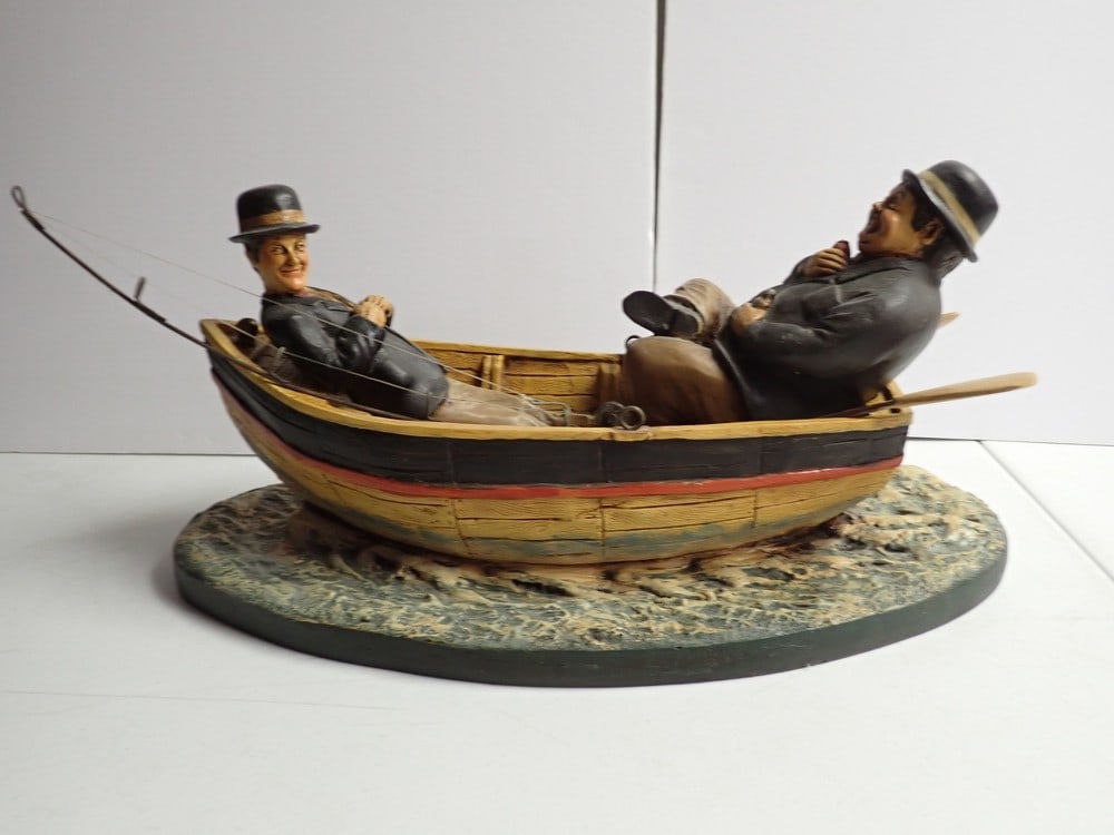 Laurel and Hardy Rowboat with 18" wide Shark. Resin: Resin Rowboat with Laurel and Hardy Figurines, Fishing Pole and Oars. Sharks head is popping up next to the rowboat. 18" wide by 10" wide.