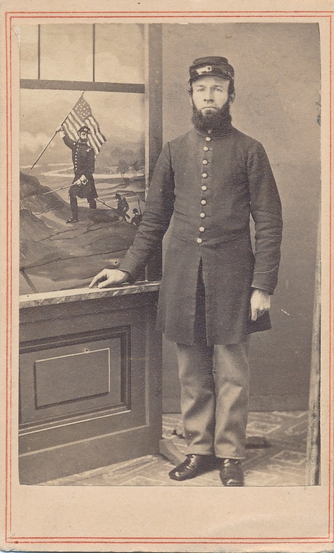 Pvt. Uriah Merritt A Co. MA 21st Infantry Wounded: Wounded 12/13/1862 Fredericksburg, VA. Background in window design shows a soldier holding a flag in window design. Carte de visite.