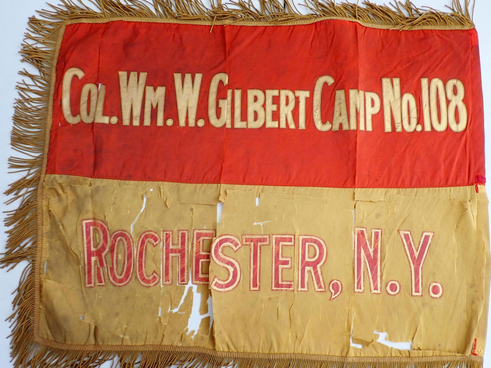 Col. Wm. W. Gilbert, Camp # 108 Rochester Banner: Col. Wm. W. Gilbert, Camp No. 108 Rochester, NY Banner. Silk fringed banner Gold leaf lettering. 18" x 22". Condition top of banner has light tearing. Bottom has considerable tearing. Should be framed