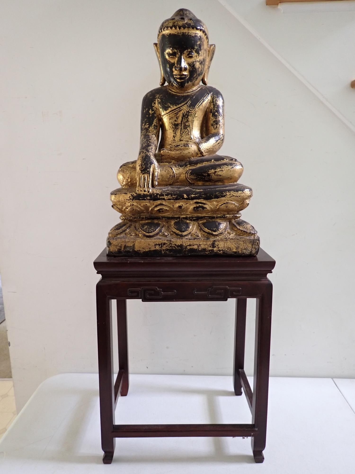 Asian Wooden Buddha Figure includes stand: Gold painted (missing some paint) wooden Buddha figure. With 20th Century. Stand. Figure 21" height. 14 1/2" x 10 1/2" x 18 1/2" stand. Stand surface has scuffs.