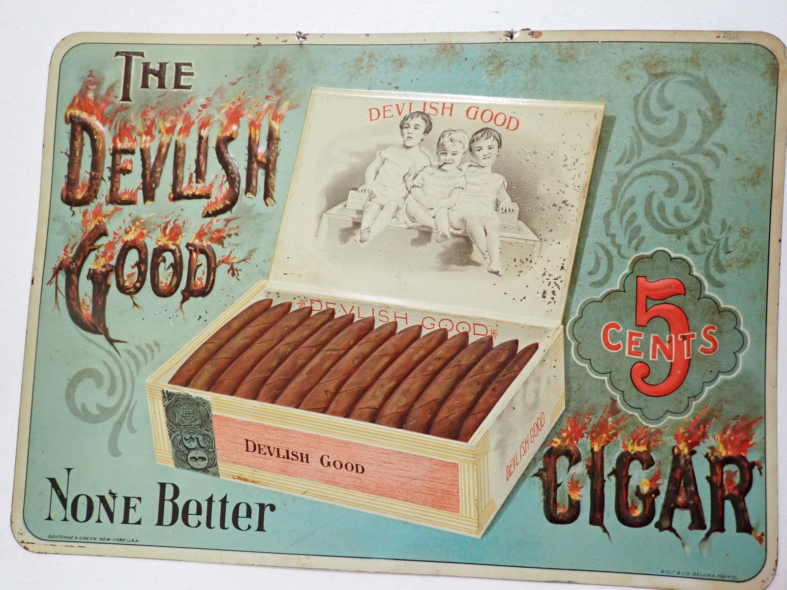 The Devilish Good 5 cents Cigars Advertising Sign: "The Devilish Good 5 cents Cigar None Better." embossed tin sign. "Senteene & Green, New York, U.S.A. Wolf & Co. Selling Agents." 10" x 14" Some paint chipping noticeable. Some discoloration at top.