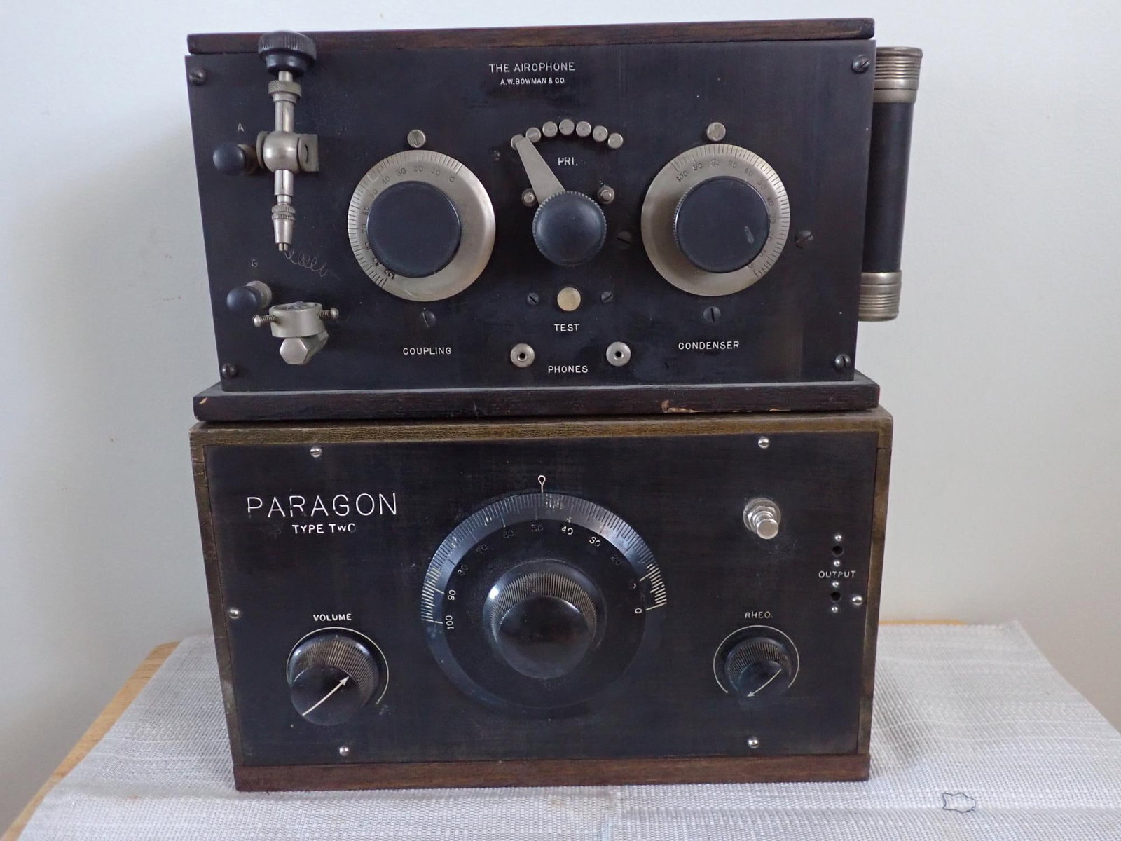 The Airophone Radio Receiver and Paragon Tube Radio: The Airophone Radio Receiver made by A.W. Bowman & Co in wooden case with instruction pamphlet. "Handle" contains original battery. 1924 AMCO Paragon Type 2 tube radio in wooden case; lid lifts to