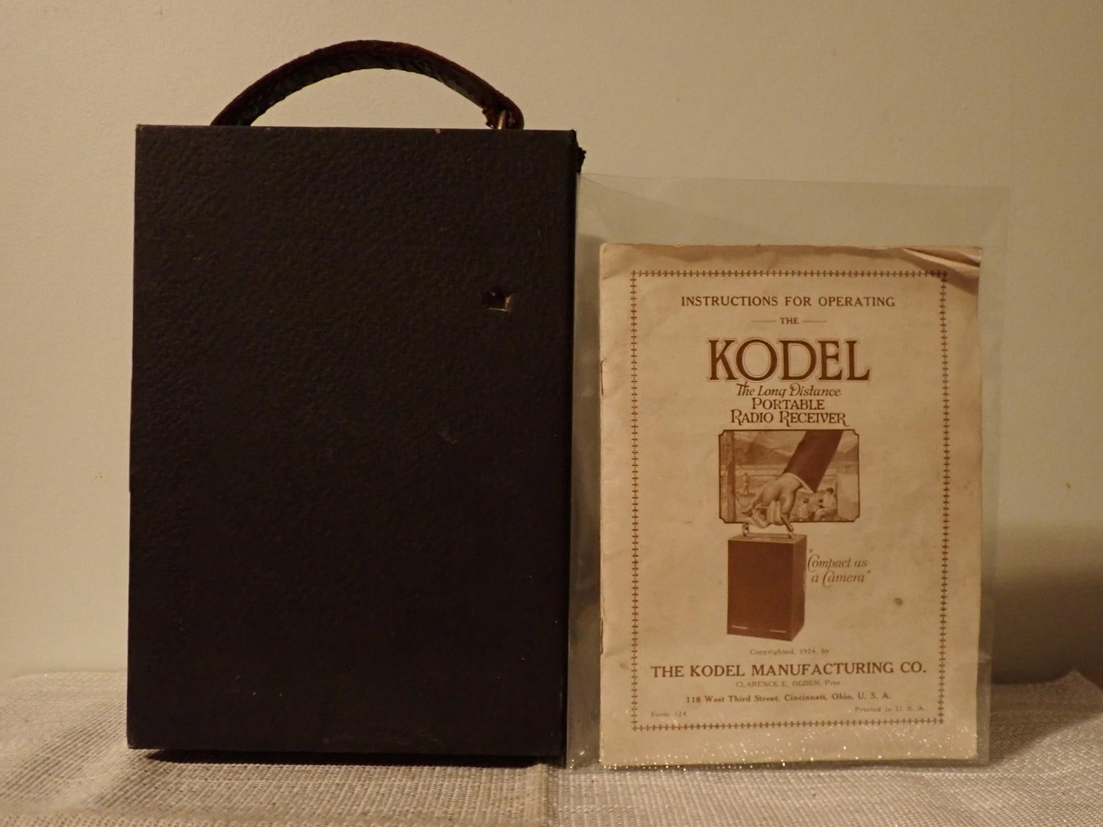 Kodel Portable Radio Receiver: "The Camera of Radio"; made by the Kodel Manufacturing Company. Portable; back opens to show RCA Tube, wiring, coil, etc. Front panel opens when unlatched and is attached by is very loose.