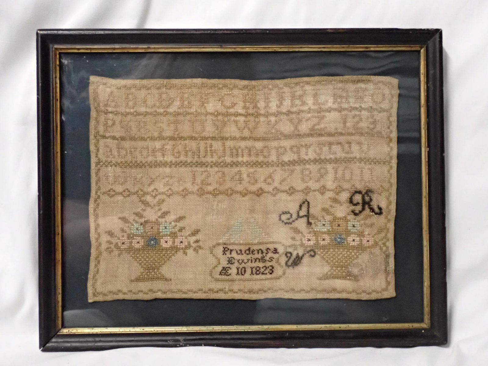 1823 Prudensa Ewing sampler: Prudensa Ewing's AE 10 1823 depicts alphabet numbers 2 baskets of flowers Frame 10 3/4" x 13 3/4" sampler 7 1/2" x 10 1/2"