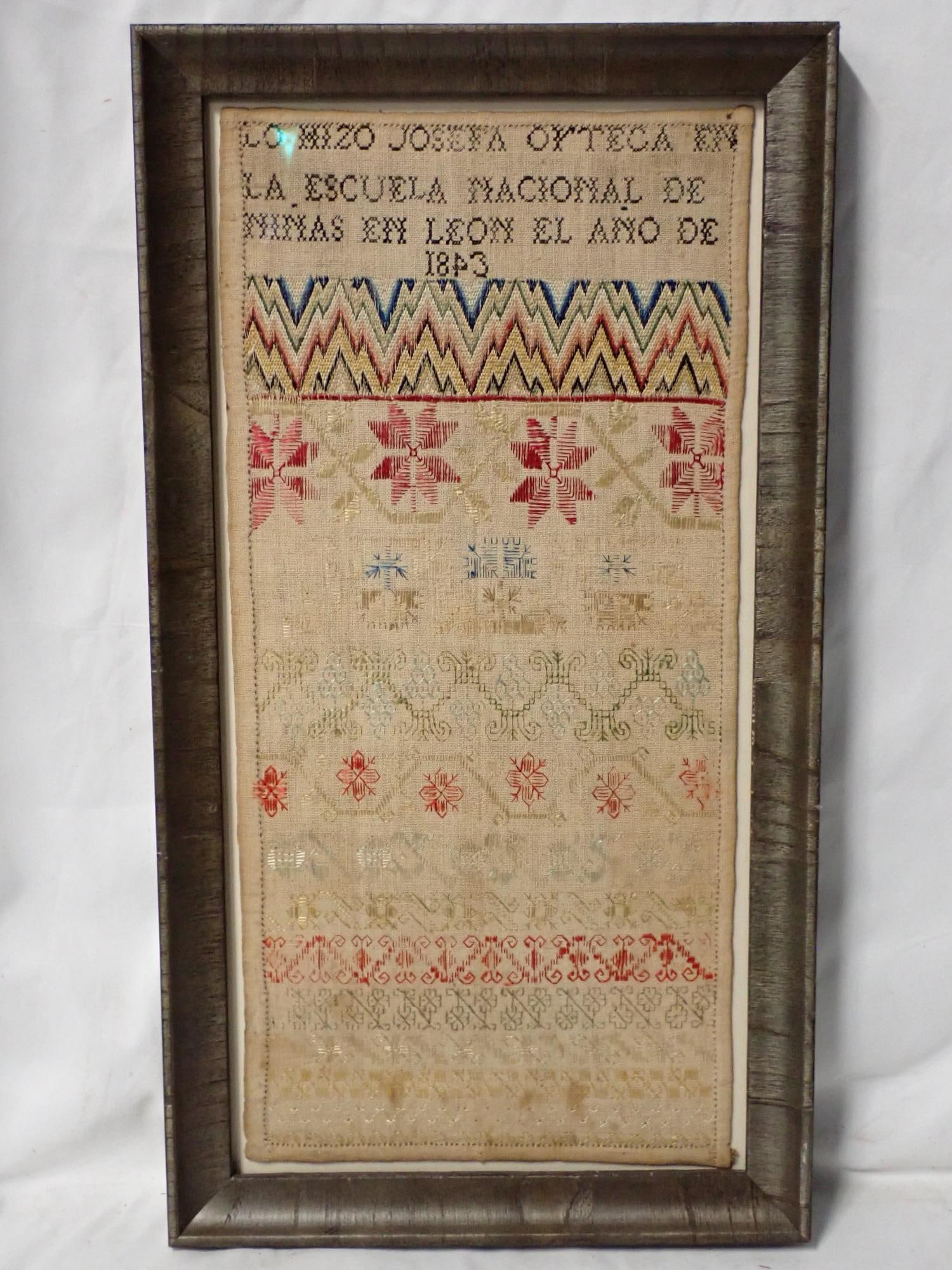 1843 Josefa Oyteca Sampler: Lo Hizo Josefa Ortega la escula Nacional De Ninas En Leon El Ano De 1843. Flame stitch floral geometrical Sampler . Some fading and staining on bottom or piece. frame 18 1/2" x 10." Sampler 16" x 7