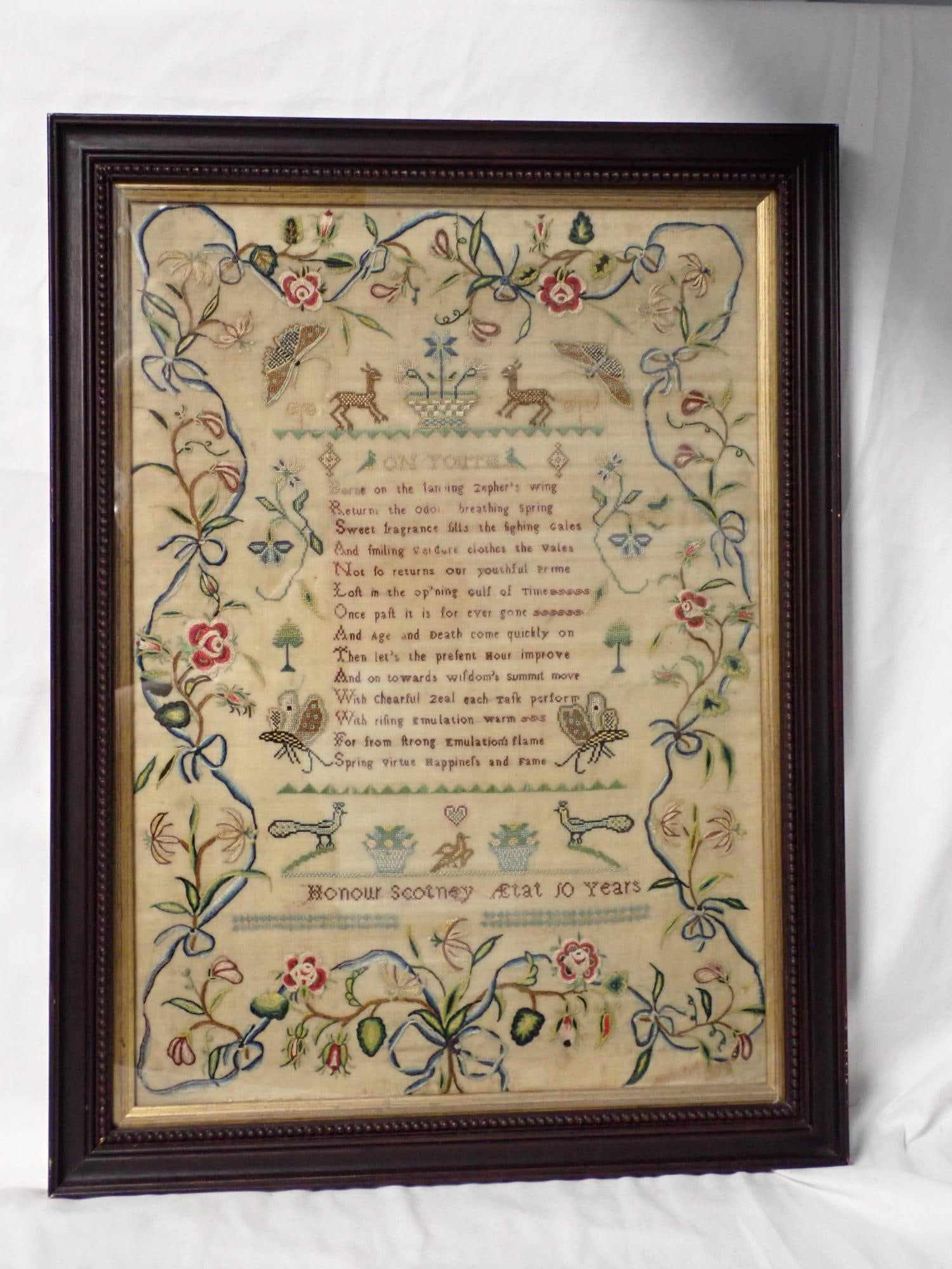 Late 17th C Honour Scotney Sampler: Honour Scotney AEtat 10 years. Brightly colored embroidery with ribbons, flowers, birds butterflies. Verse Titled- On Youth. Slight discoloration Frame 21 1/2" x 16" Sampler 18 1/4" x 13"
