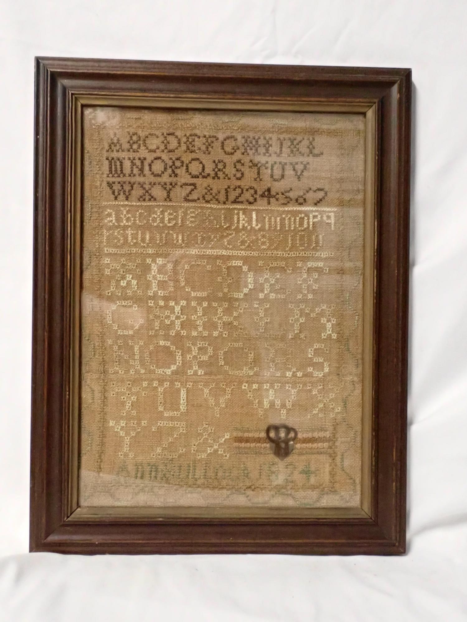 1824 Ann Bullock Sampler: Ann Bullock 1824 Alphabet numbers geometrical border, some letters done in eyelet stitch fabric heart possibly mourning art with hair?. Some fading and discoloration Frame 13 3/4" x 10 1/2" Sampler 11