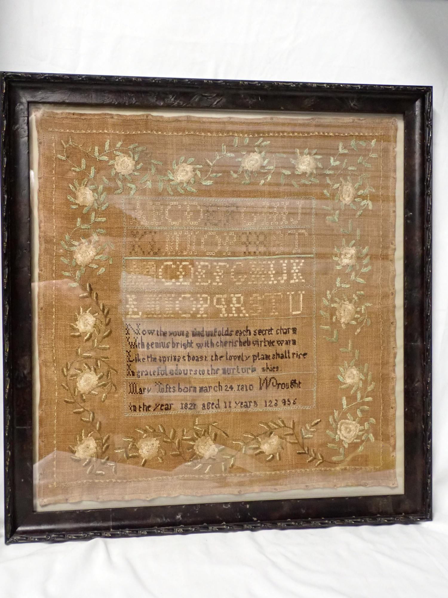 1821 Mary Tufts Sampler: Mary Tufts born march 24, 1810 Wrought in the year 1821 aged 11 years. Verse in center, Partial Alphabet. Vince and floral border. Fabric discoloration. Frame 20" x 19" Sampler 17" x 16"
