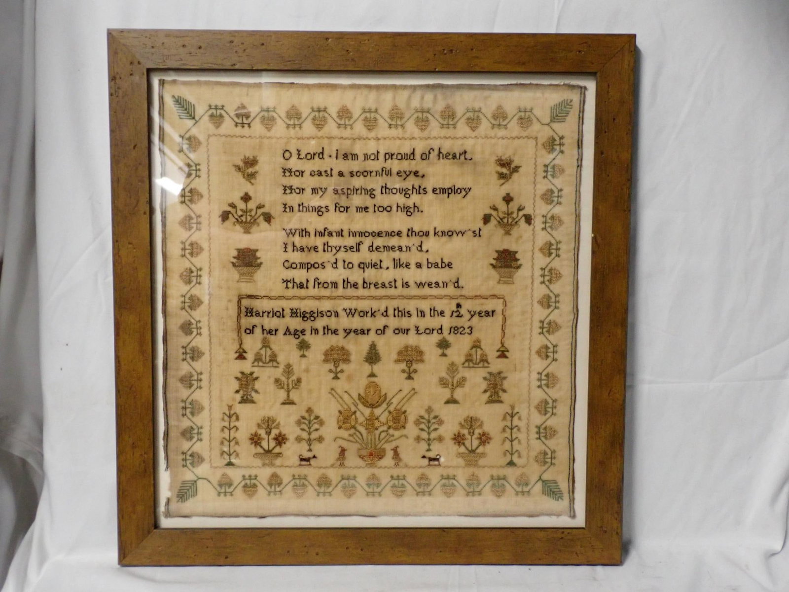 1823 Harriot Higglson Sampler: Harriot Higglson Work'd this in the 12th year of her Age in the year of our Lord 1823. Religious verse at top, motif floral, animals, birds and trees. Vine and fruit border. Some fabric loss and fabri