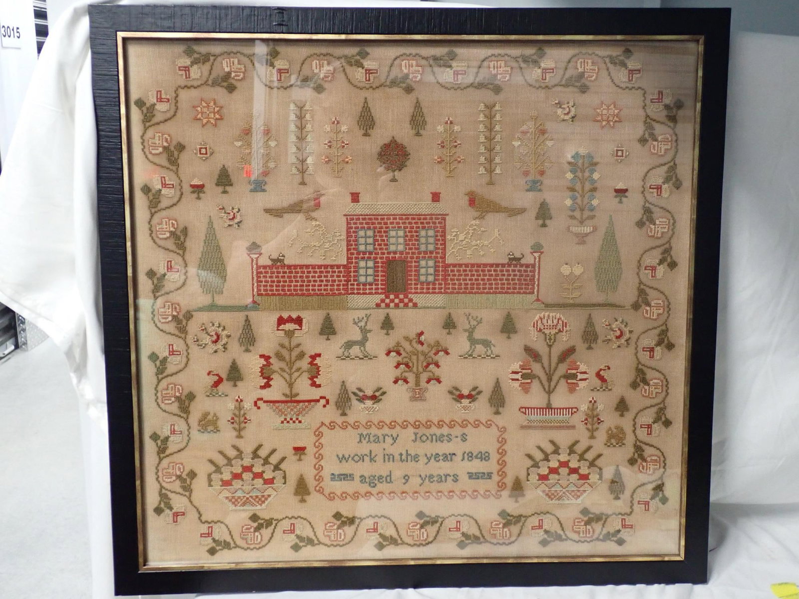 1848 Mary Jones Sampler: Mary Jones's work in the year 1848 aged 9 years. Motif house, birds, flowers animals, trees. Nice and floral border. Some slight staining. Vine and floral border. Frame 25" x 26 1/4". Sampler 22 1/4"