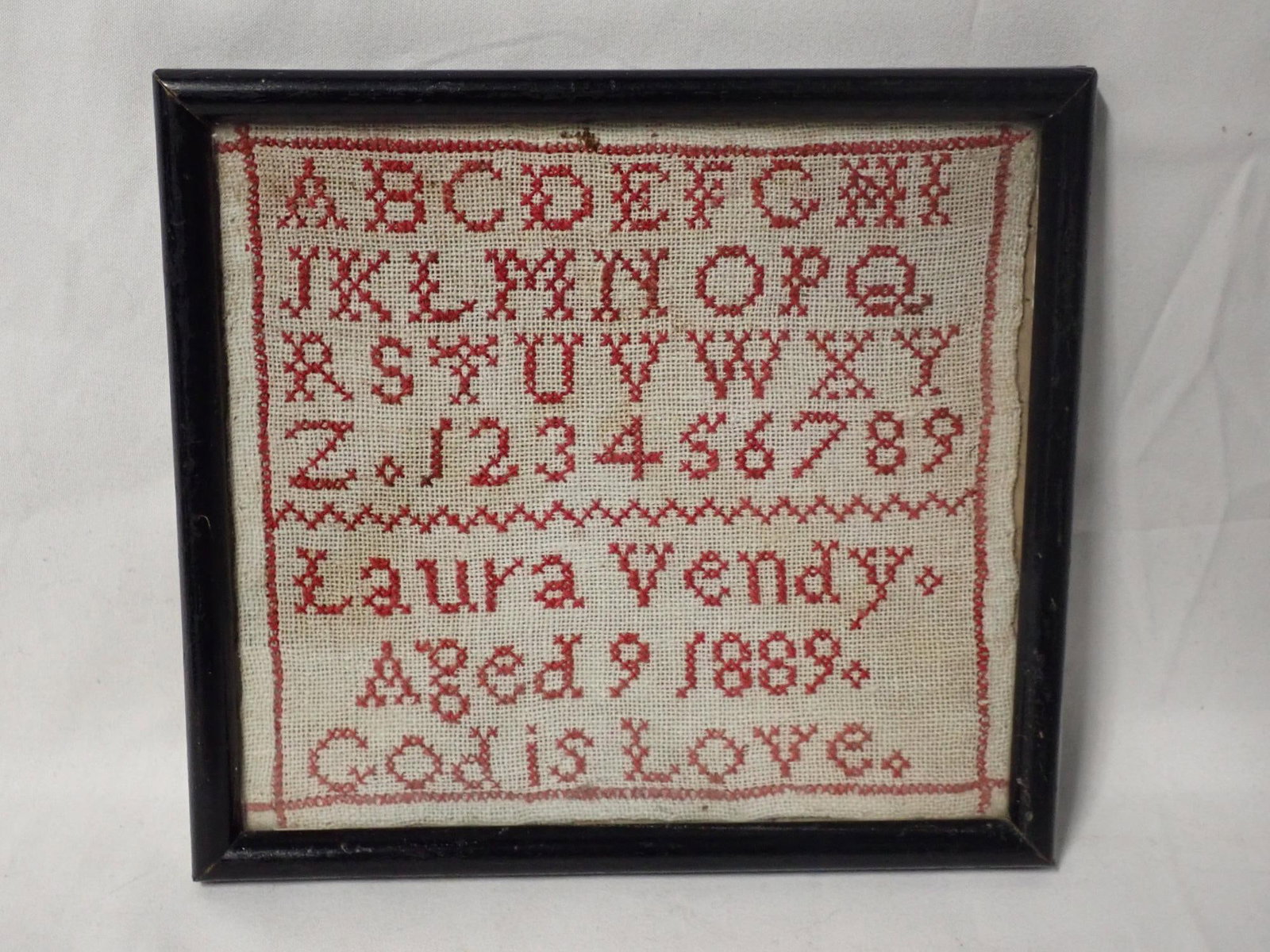 1889 Laura Vendy Sampler: Laura Vendy Aged 9 1889 God is love red stitching Frame 6" x 6 1/2" Sampler 5 1/4" x 5 3/4"
