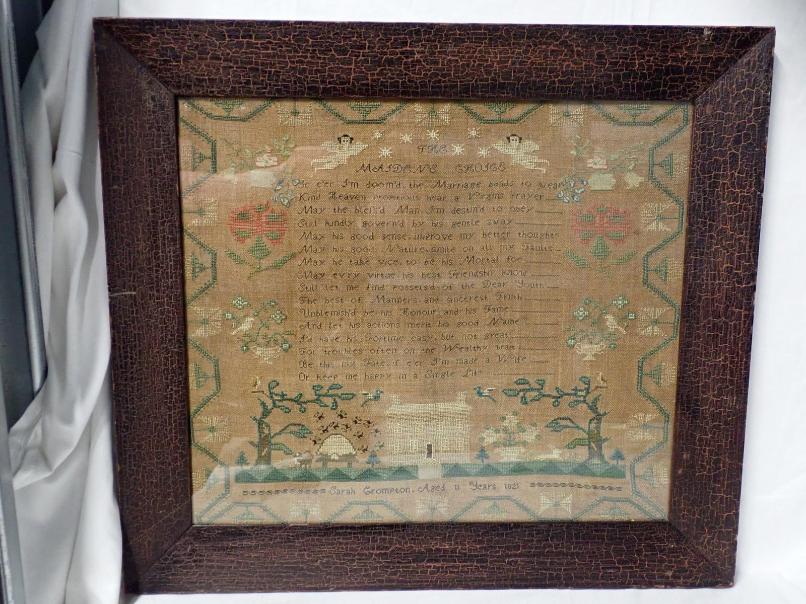 1821 Sarah Crompton Sampler: Sara Crompton Aged 11 Years 1821. "Verse titled The Maidens Choice" at top. Motif is Cherubs, flowers house and animals. Vine and floral border. Frame 19" x 21" Sampler 14 1/4" x 16 1/2"