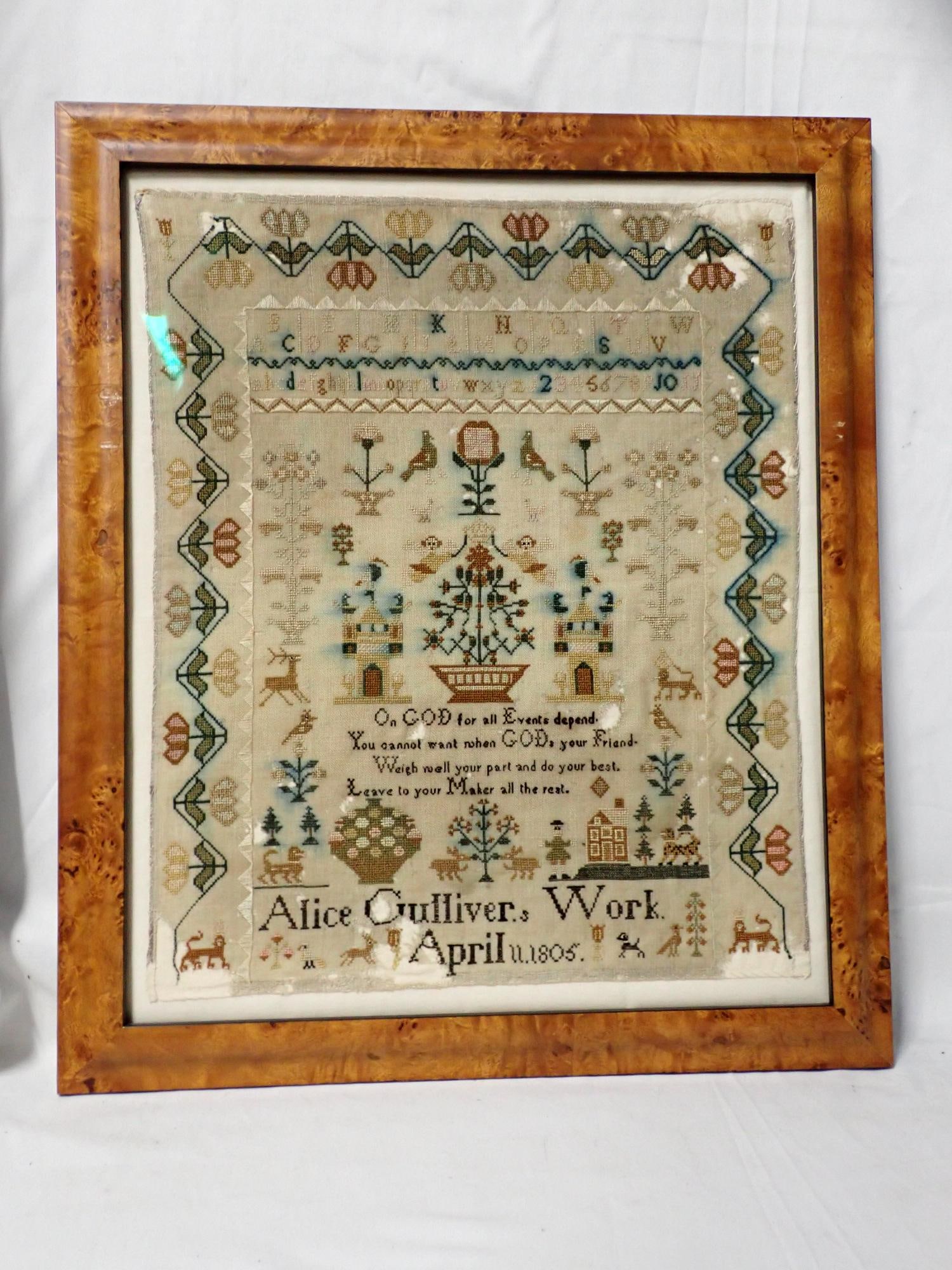 1805 Alice Gulliver Sampler: Alice Gullivers Work April 11 1805. Religious verse in center. Alphabet and number Motif Birds, floral baskets animals Border Vine and flowers. Fabric loss and staining. Frame 19 x 16 Sampler 15 x 12 