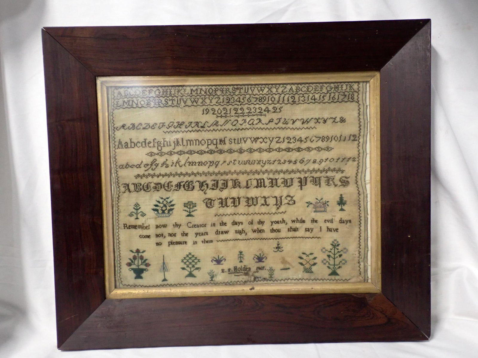 1865 E.F.(?) Holden Sampler: E.F. Holden 1865 Alphabet and numbers Religious verse at bottom. Motif flowers. Some fabric loss and discoloration. Frame 16 1/4 x 19 1/4 Sampler 10 1/2 x 13 1/4