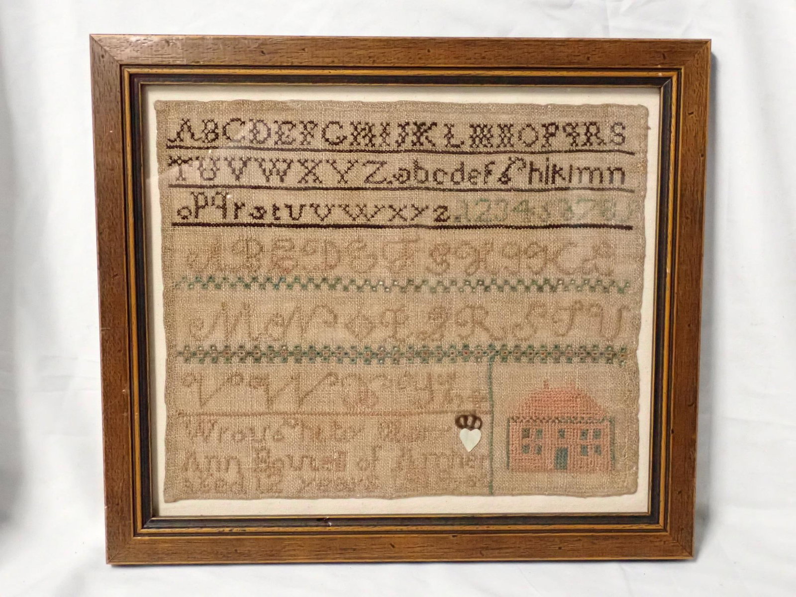 1818 Mary Ann Boutell Sampler: Wrought by Ann Boutell of Amherst aged 12 years 1818. Alphabet and numbers, house bottom corner. Small fabric heart next to Mary. Fabric discoloration Frame 13 x 14 3/4 Sampler 10 x 11 3/4