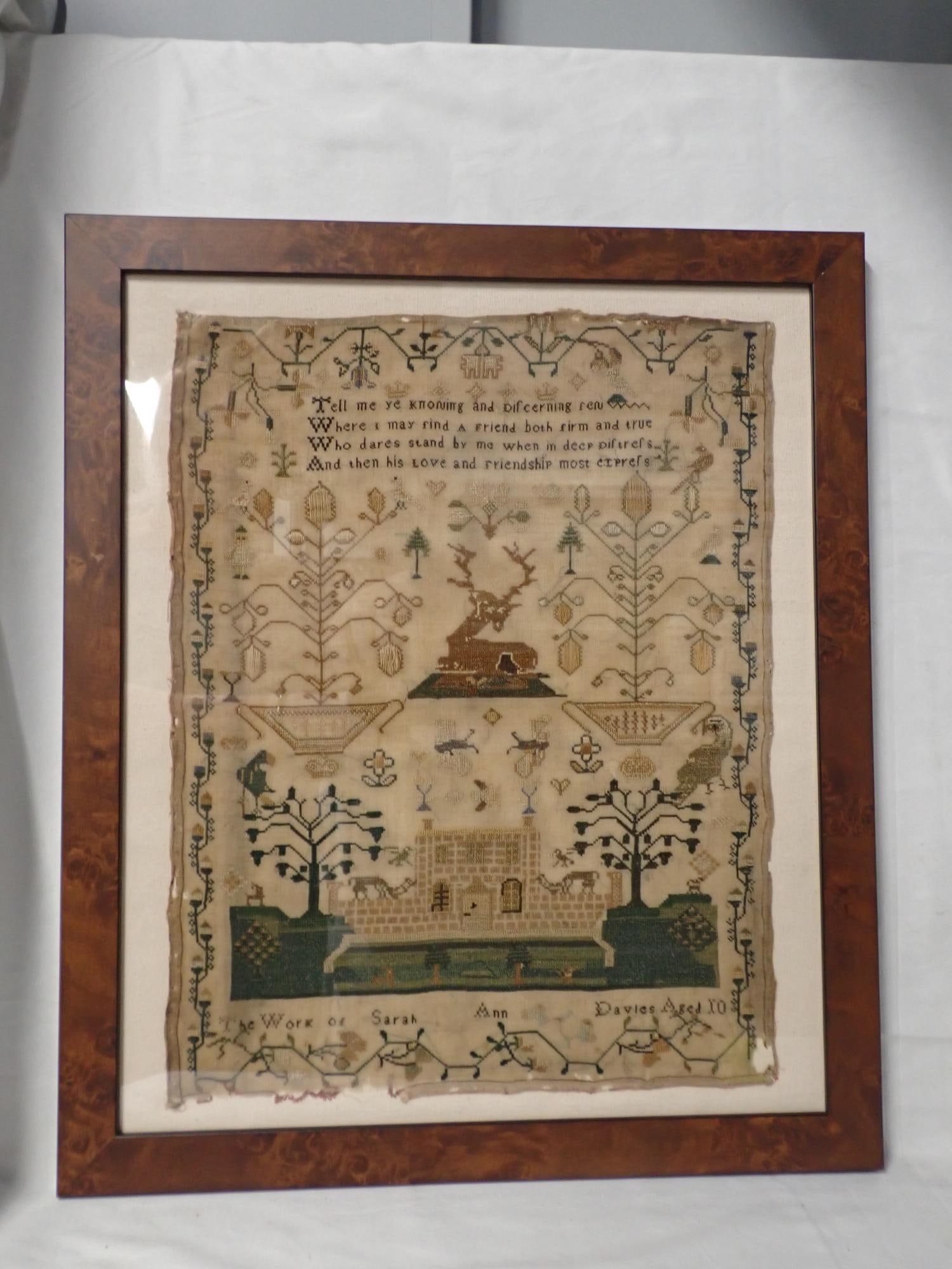 19th Century Sara Ann Davies Sampler: Work of Sara Ann Davies Aged 10. Verse at top. Motif Stag in center. House at bottom. Motif Animals birds, trees, Vine and floral border. Some fabric loss and discoloration Frame 20 x 17 Sampler 16