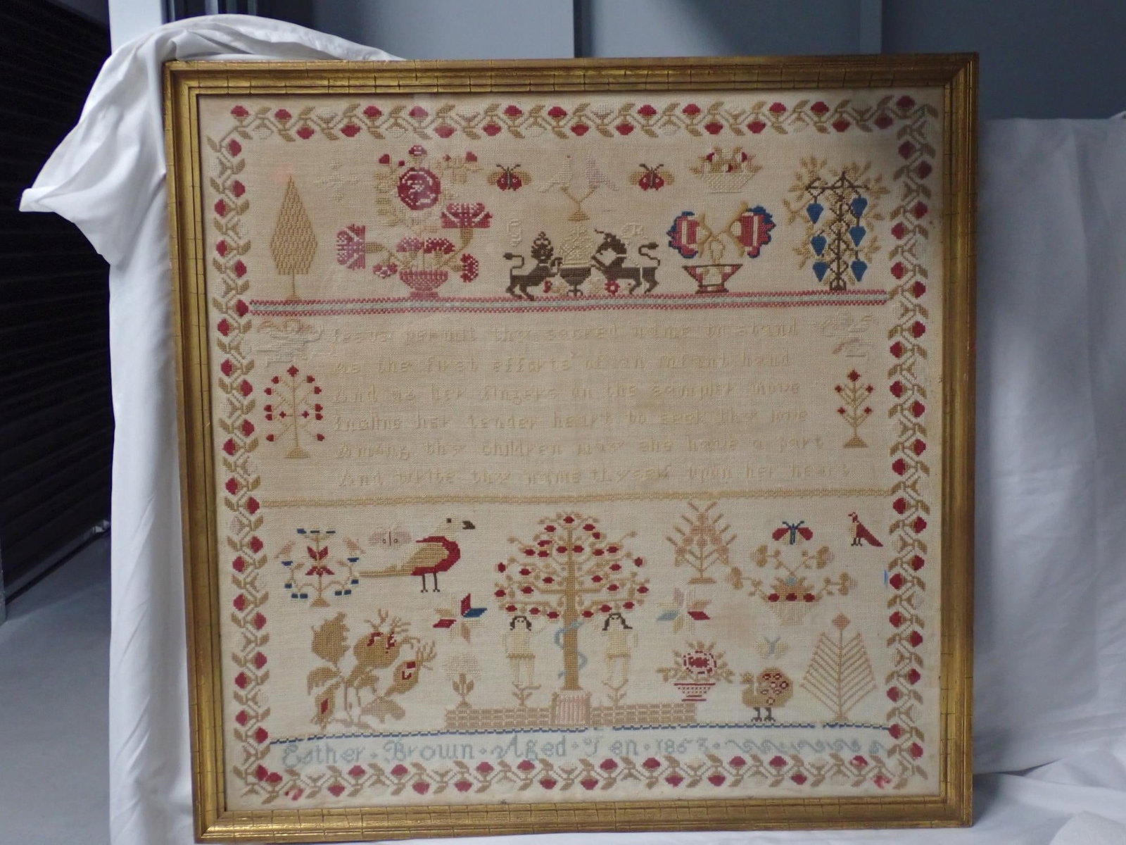 1853 Esther Brown Sampler: Esther Brown Aged Ten 1853. Religious verse in center. Motif Adam and Eve lions birds, flowers peacock. Vine and floral border. Verse is hard to read. Otherwise good condition Frame 26 1/8 x 26 1/2