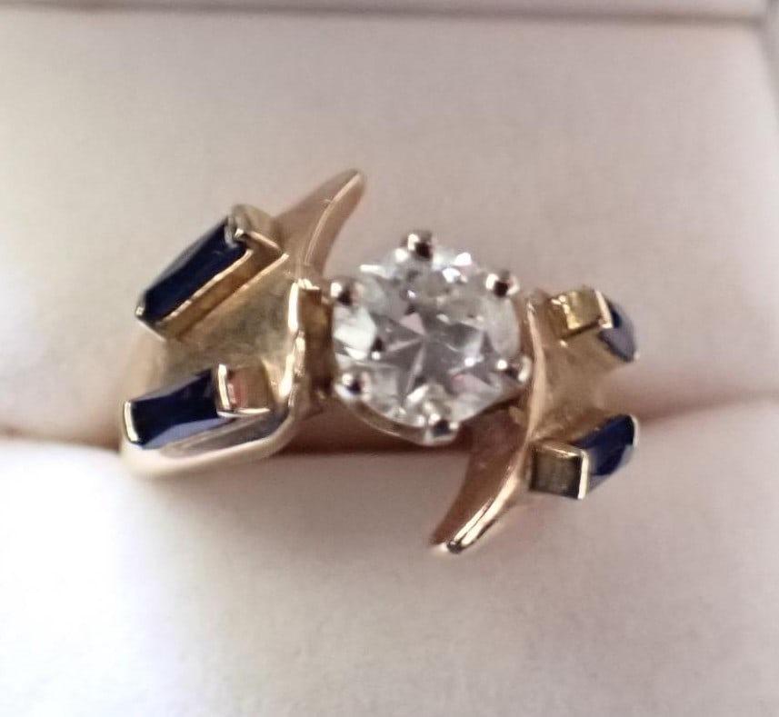 14K Diamond Ring with Sapphires - 1 CT Center Stone: 14K Yellow Gold Diamond Ring Containing (4) Baguette Sapphires and (1) Round European Cut Diamond Measuring Approximately 6 x 4.2 mm at approximately 1.00 CT. The Diamond is of High White color with