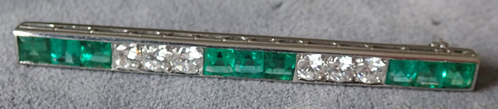 Platinum Emerald and Diamond Cartier Bar Pin: Platinum emerald and diamond bar pin. The pin features nine square French cut emeralds of fine quality and cutting with strong and even saturation, few inclusions, and excellent match. The emeralds