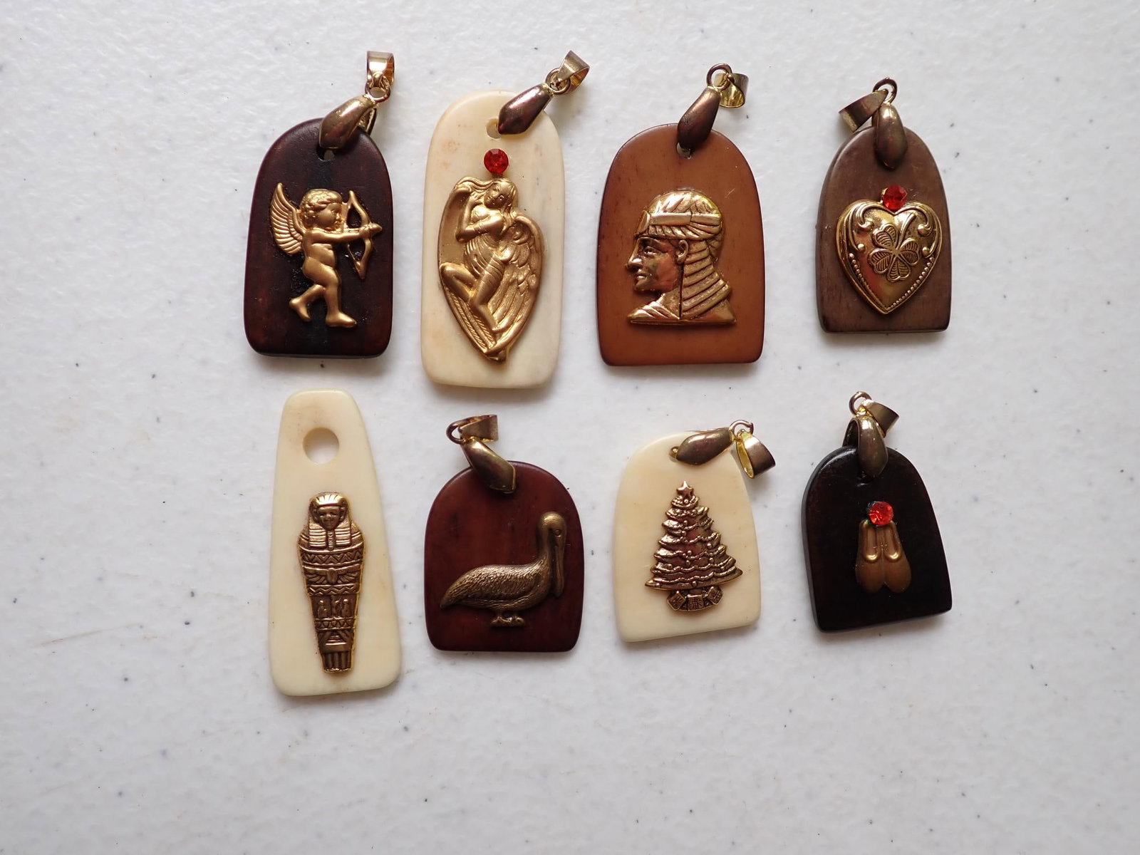 (8) 18K Gold Plated Pendants: Christmas Tree, Heart, Cupid, Ballerina Shoes, Crane, Egyptian Symbols and Other. Sizes range from 1" tall to 1 3/4" Tall. One bail is missing. Bails marked 18K Plated.