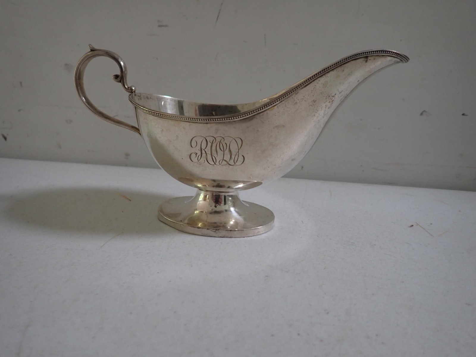 Sterling Silver Gravy Boat: 8" wide Beaded Top. Marked Sterling "M" 1026. Monogrammed. Rim Bent. 7.2 troy ounces.